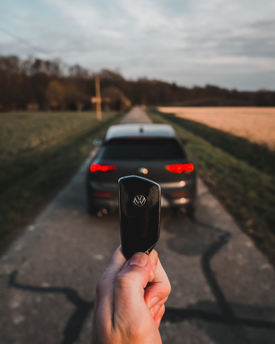 person holding black smartphone during daytime with car keys after Vehicle Title Transfers went through